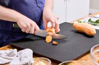 A person slices sweet potato with the HexClad 8 Inch Damascus Steel Chef’s Knife