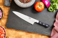 The Mac Knife 8-Inch Hollow Edge Chef's Knife with veggies on a cutting board 