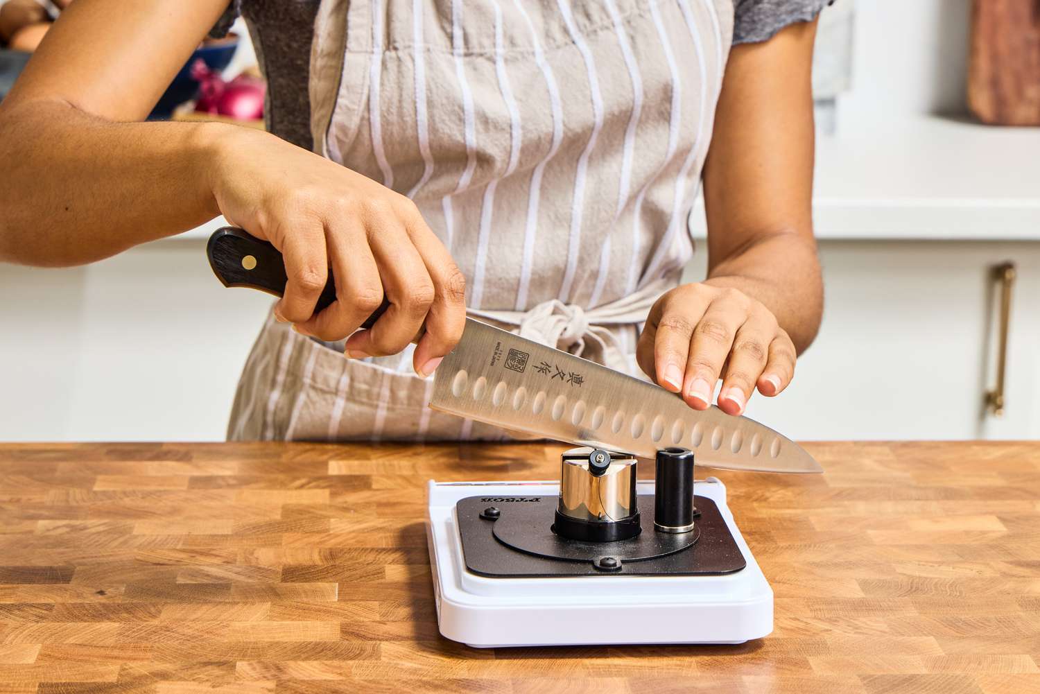 A person sharpens the edge of Mac Knife 8-Inch Hollow Edge Chef's Knife 