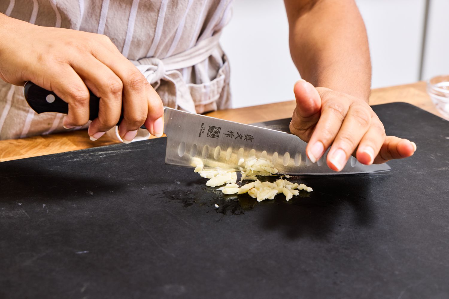 A person chops garlic with the Mac Knife 8-Inch Hollow Edge Chef's Knife