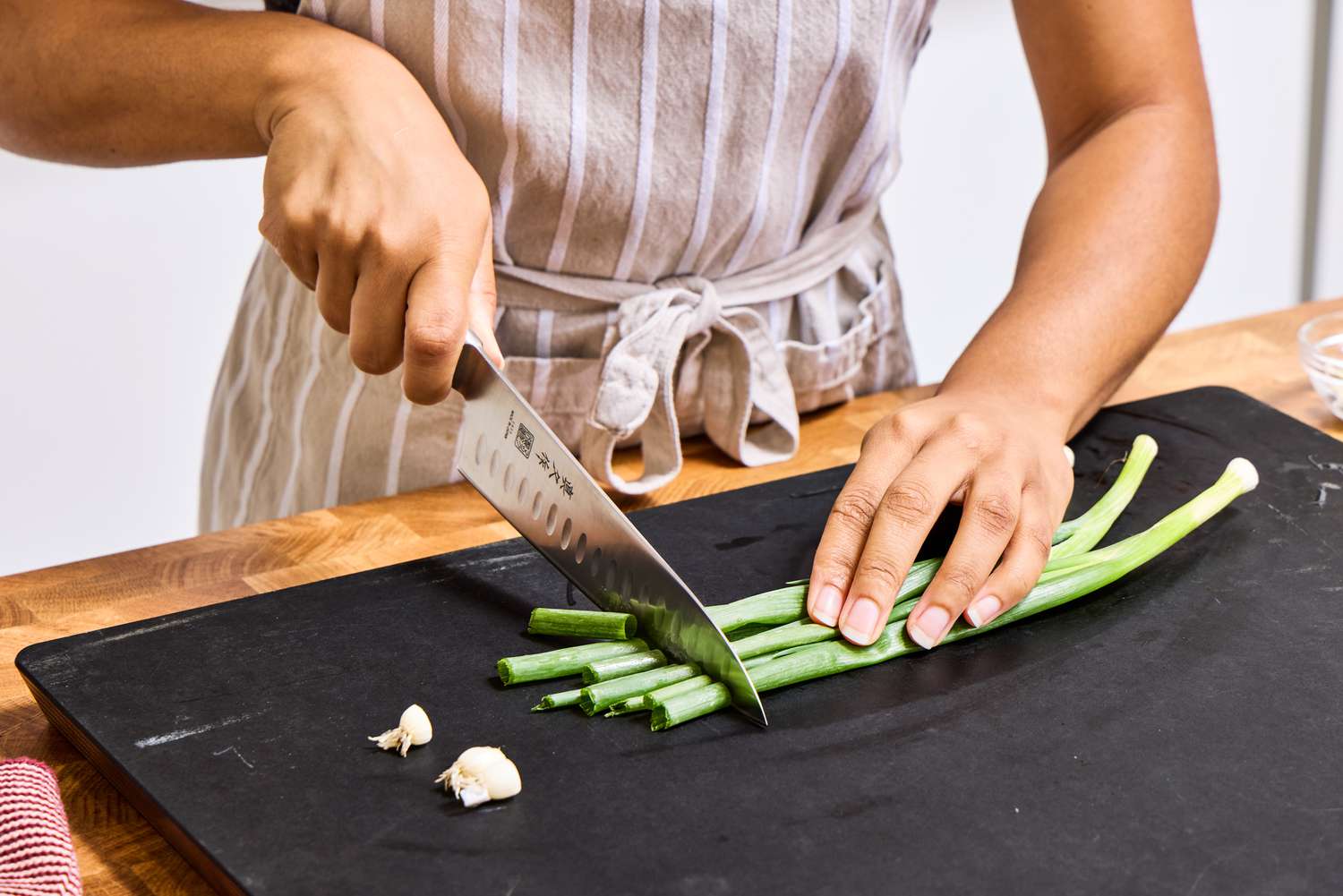 A person dices spring onions with the Mac Knife 8-Inch Hollow Edge Chef's Knife