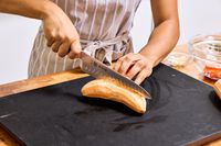 A person slices sweet potato with the Mac Knife 8-Inch Hollow Edge Chef's Knife