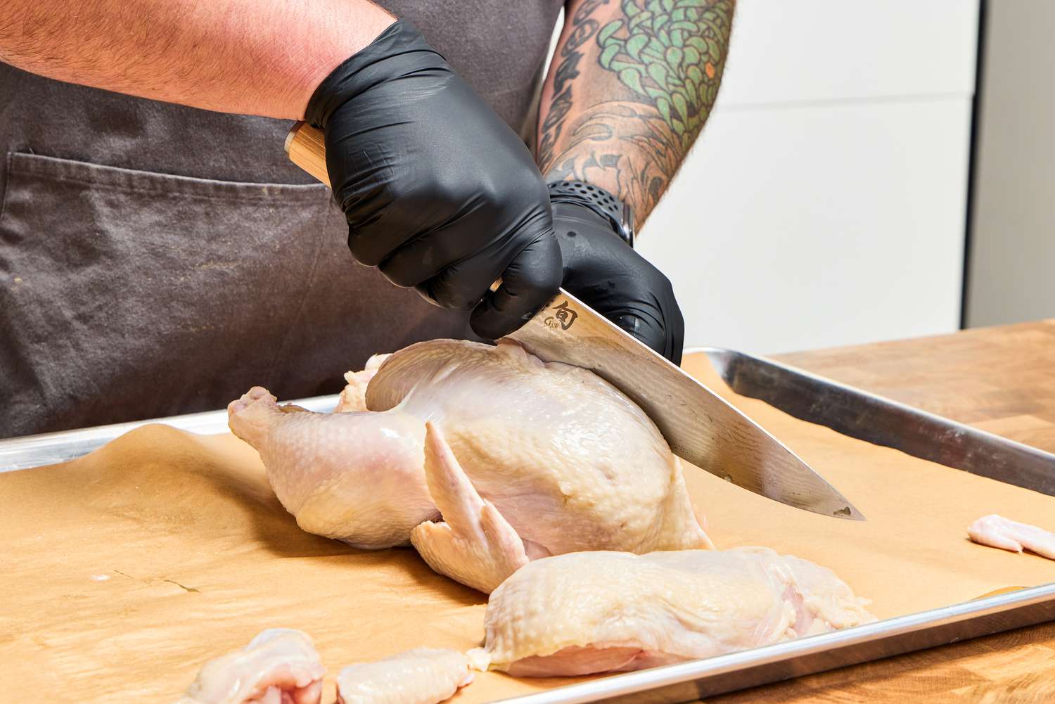 A close-up of person slices chicken wings with the Shun Classic Chef's 8-Inch Knife