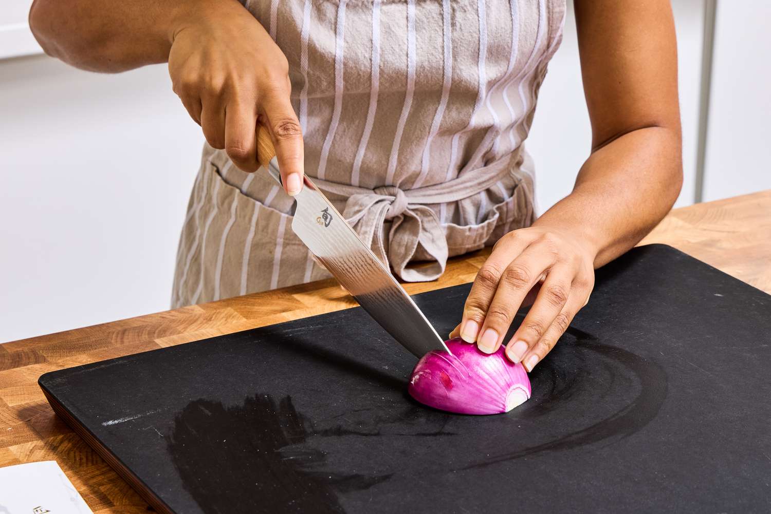 A person slices onion with the Shun Classic Chef's 8-Inch Knife