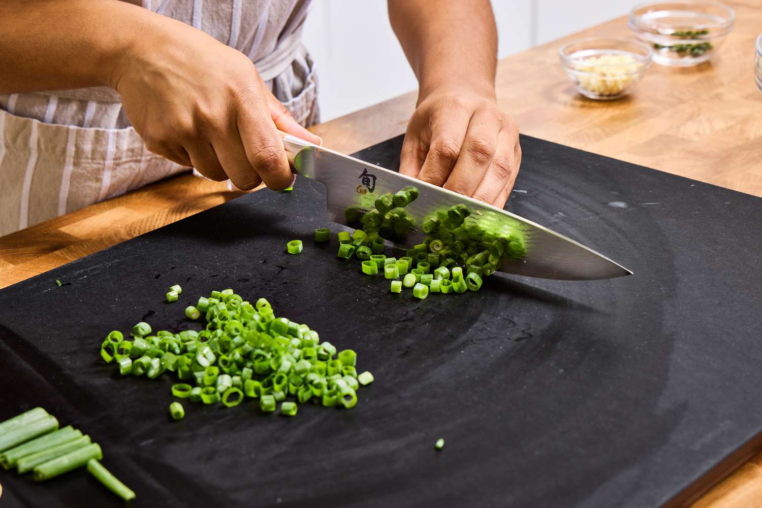 A person slices scallions with the Shun Classic Chef's 8-Inch Knife