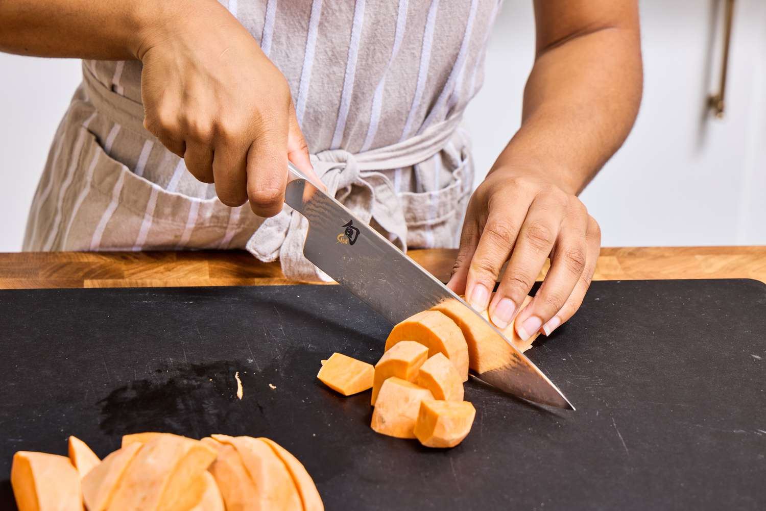 A person dices sweet potato with the Shun Classic Chef's 8-Inch Knife