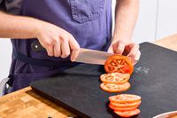 A person slices tomato with the Wusthof 8-Inch Classic Chef's Knife