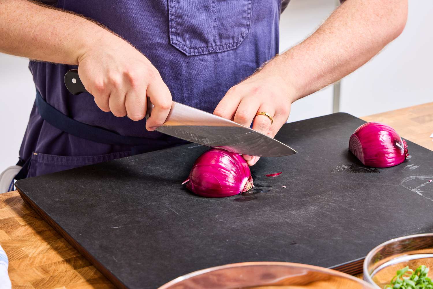 A person slices onion with the Wusthof 8-Inch Classic Chef's Knife on a cutting board