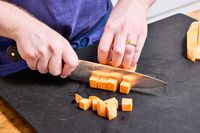 A person chops sweet potato with the Wusthof 8-Inch Classic Chef's Knife