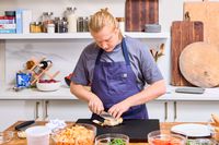 A person slices meat with the Wusthof 8-Inch Classic Chef's Knife in a kitchen