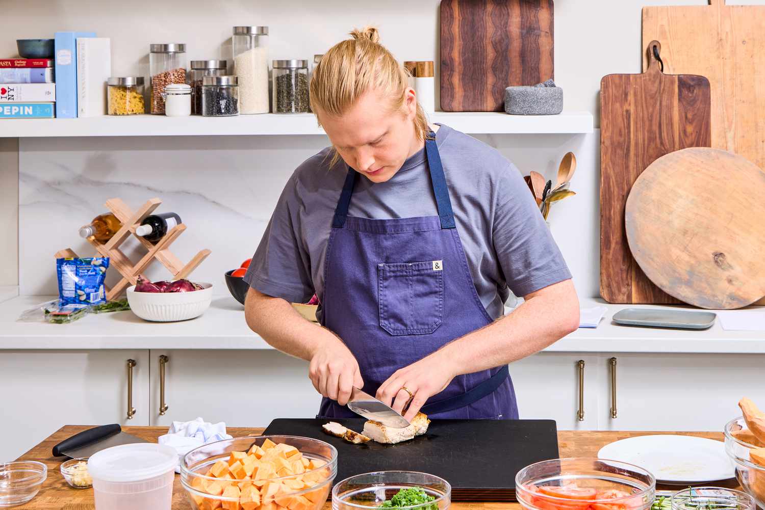 A person slices meat with the Wusthof 8-Inch Classic Chef's Knife in a kitchen