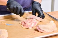 A person slices chicken with the Wusthof 8-Inch Classic Chef's Knife