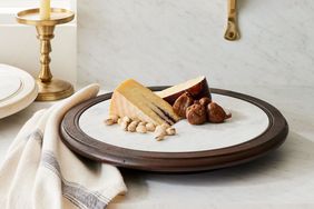 Two cheese wedges, fruit and nuts on a marble lazy susan 