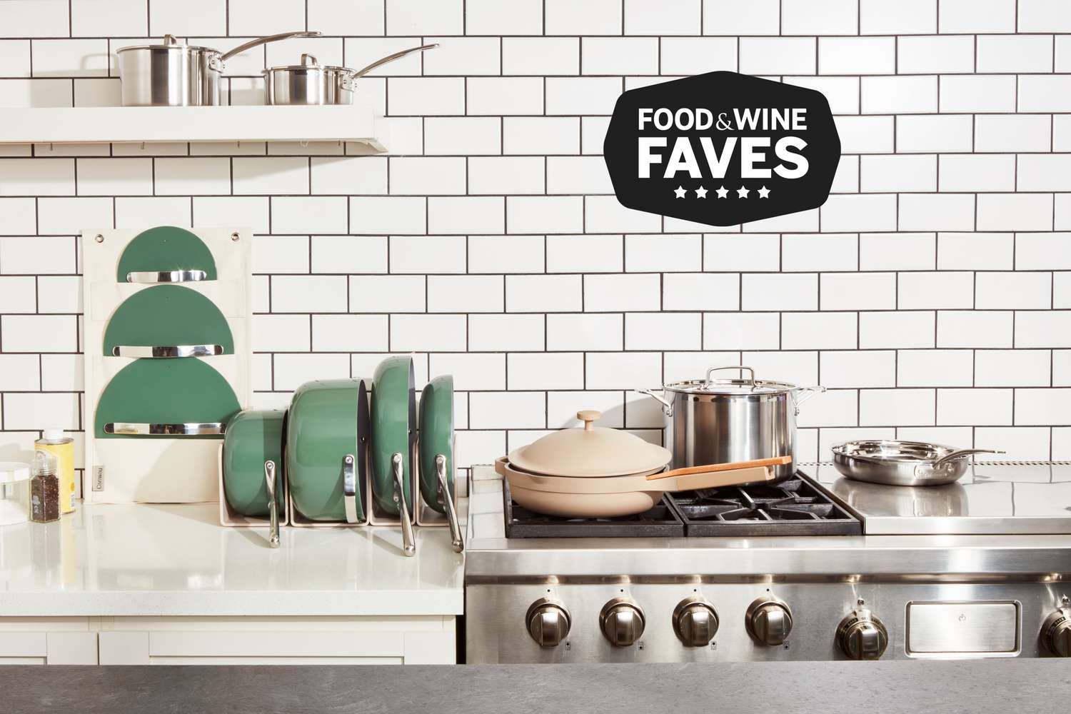 An assortment of non-toxic cookware we recommend displayed side-by-side on marble countertop, shelf, and gas stovetop