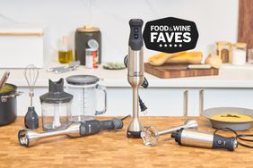 Three immersion blenders on a counter with a bowl of soup