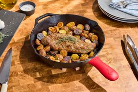 Lodge cast iron skillet with red handle, steak, and potatoes. 