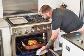 Person taking the Nordic Ware Copper Turkey Roaster with Rack from an oven