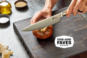 person slicing tomato with Shun knife on wooden cutting board