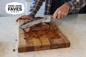 A person uses the Shun Premier Carving Knife & Meat Fork Set to cut brisket