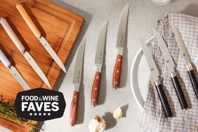 An assortment of steak knives we recommend displayed side-by-side on countertop with cutting board, plate, and towel