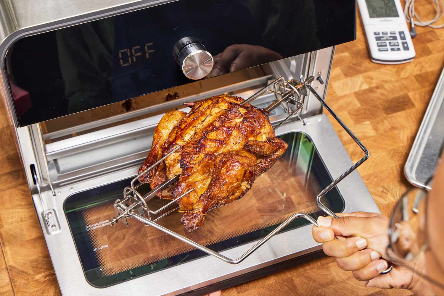 Removing a rotisserie chicken from the Instant Omni Plus Air Fryer Toaster Oven