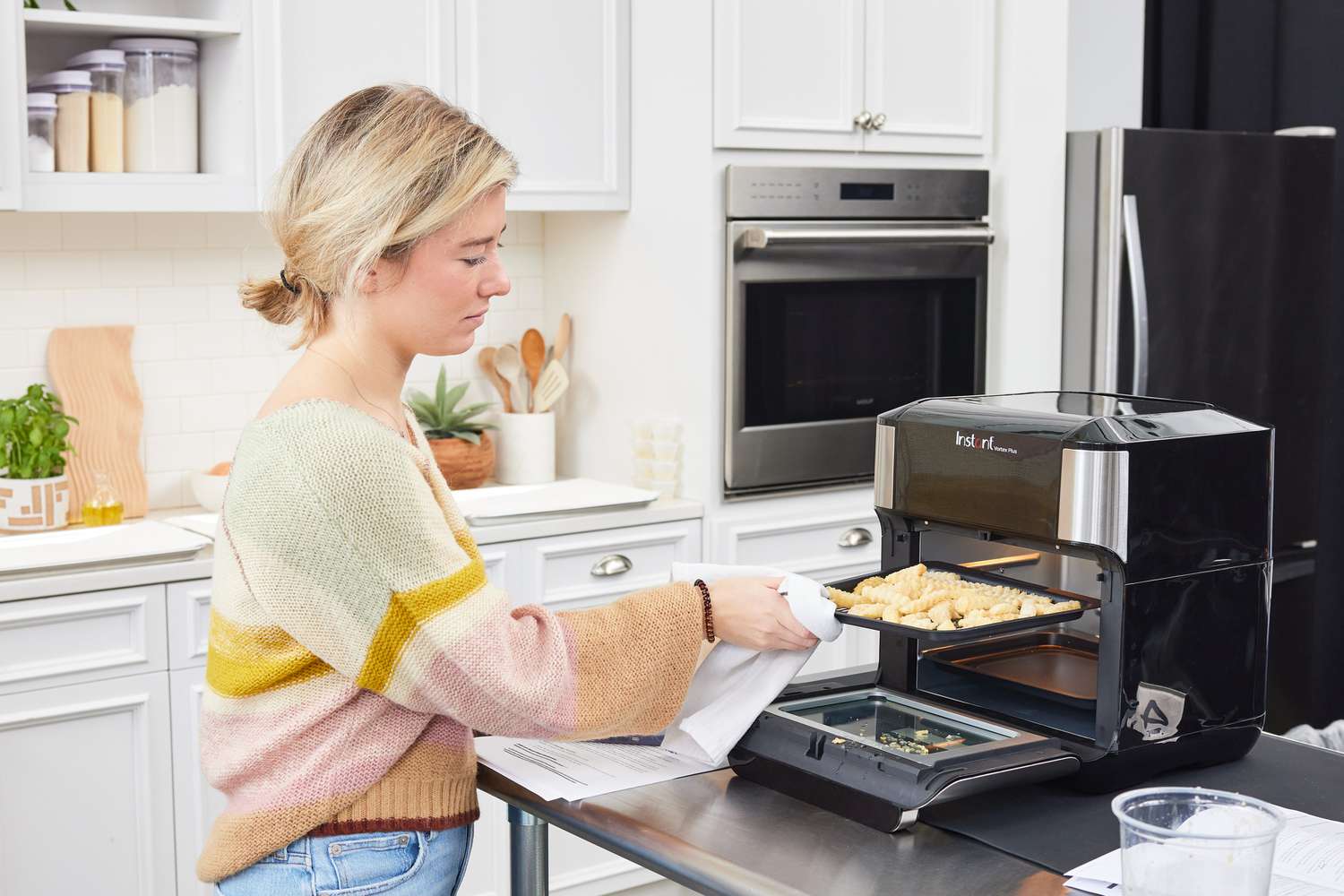 Person using towel to remove food on tray from Instant Pot Vortex Plus 10-Quart 7-in-1 Digital Air Fryer