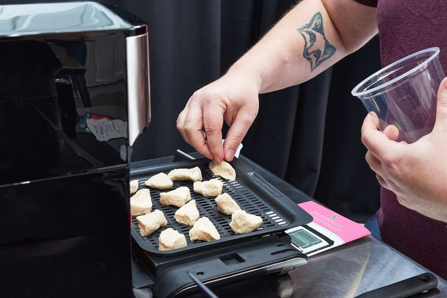 Person's hand arranging chicken chunks on tray from Instant Pot Vortex Plus 10-Quart 7-in-1 Digital Air Fryer