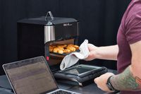 Person's hand using towel to remove food on tray from Instant Pot Vortex Plus 10-Quart 7-in-1 Digital Air Fryer