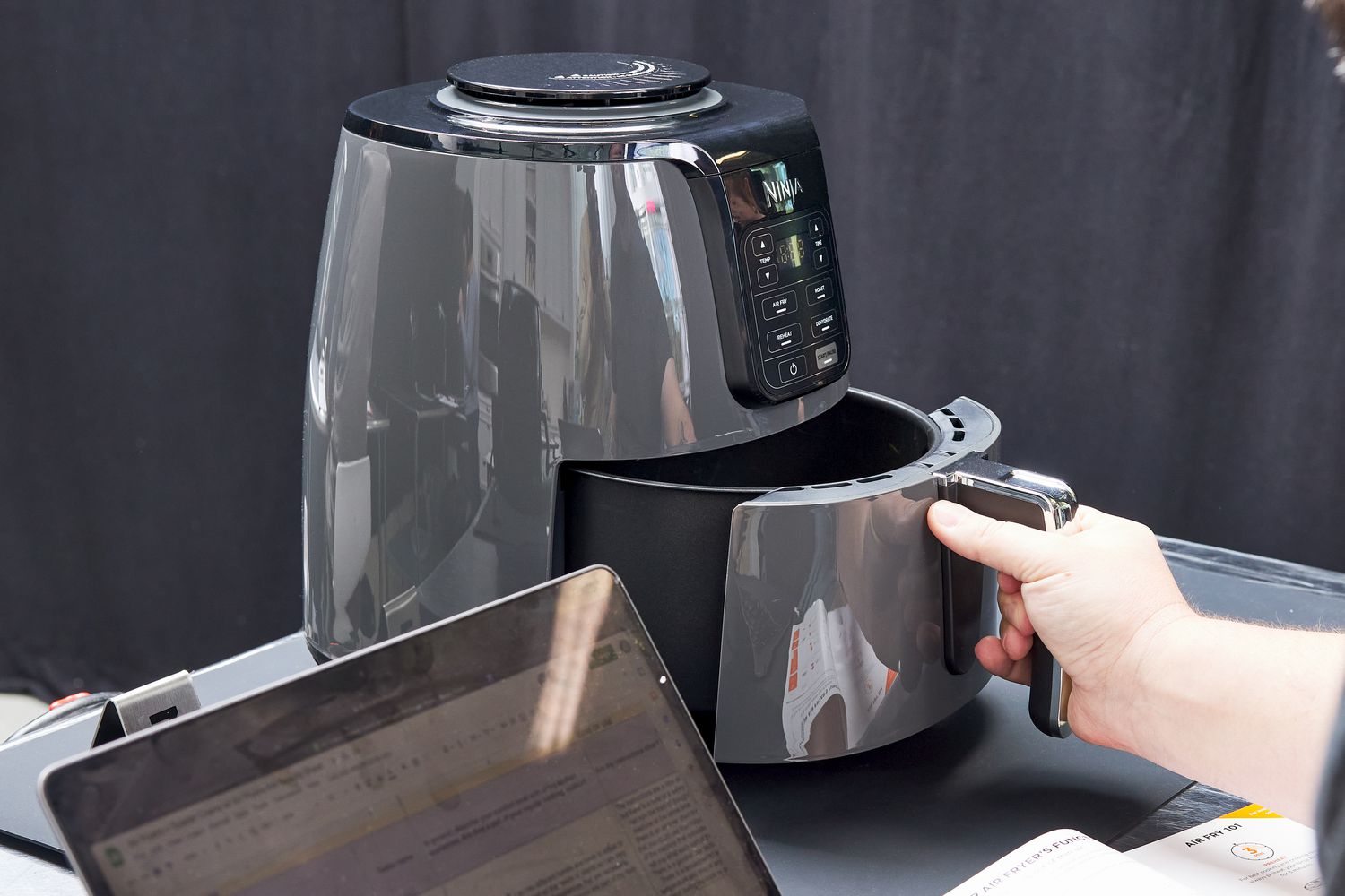 Hand removing the basket from the Ninja 4-Quart Air Fryer