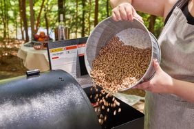 Person pouring pellets into a Traeger Pro Series 780 Wood Pellet Grill and Smoker