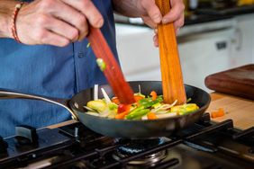 Person using 3-Piece Wood Kitchen Utensil Set to toss food while being cooked