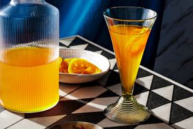 A citrus focused non-alcoholic drink on a black and white patterned table. 