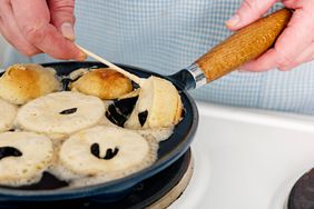 Traditional apple slices or Æbleskiver in danish being baked in a traditional cast iron skillet.