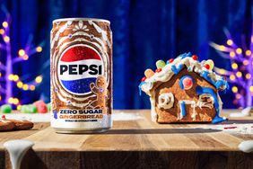 Gingerbread Pepsi on a table next to a small gingerbread house.