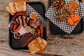 Two trays of smoked meats and sides from Distant Relatives in Austin