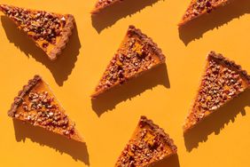 Several pieces of pumpkin cake with walnuts on orange table. 