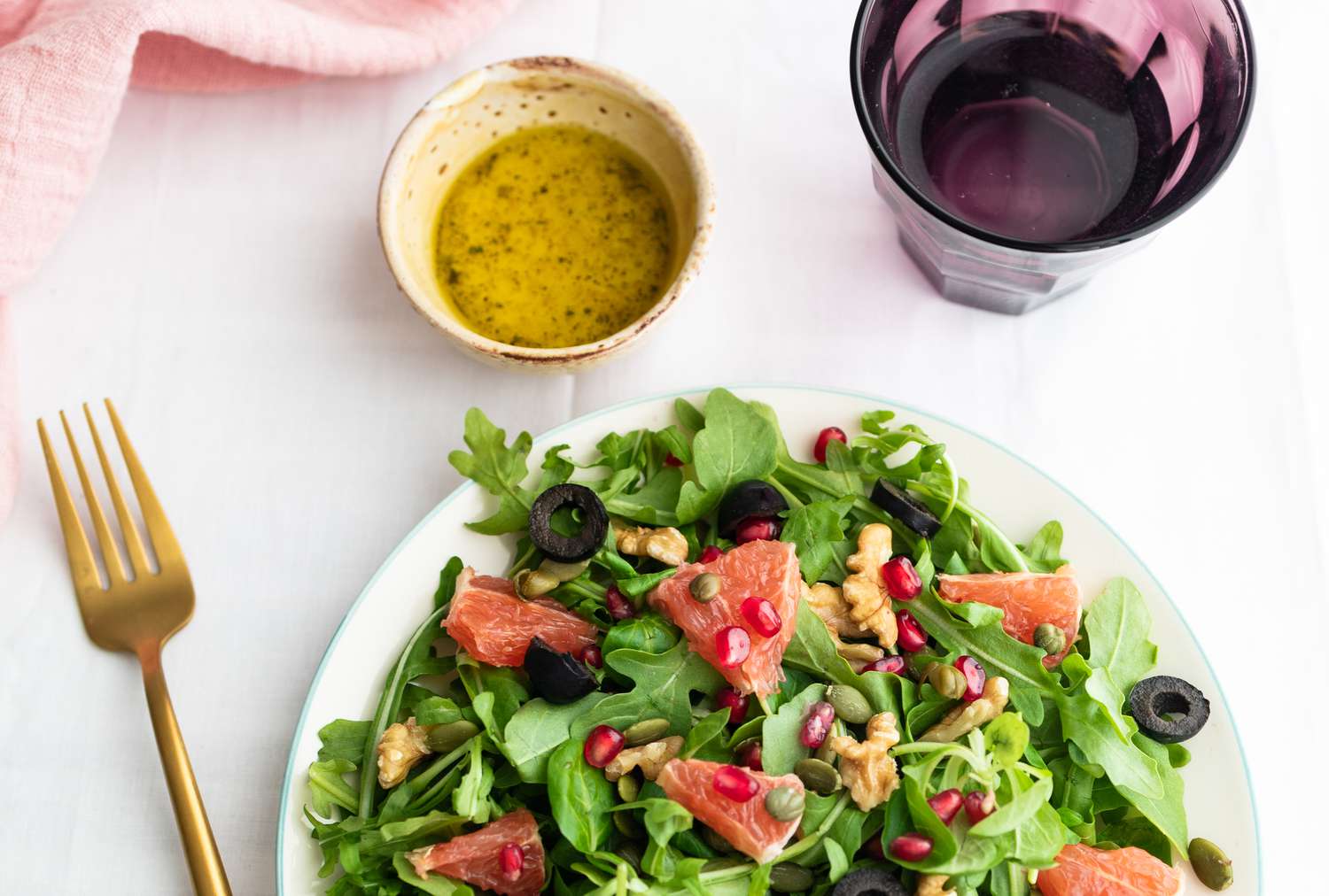 A salad with vinaigrette dressing and a glass of water. 