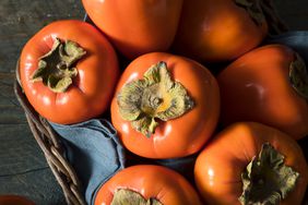 Persimmons sitting in a basket.