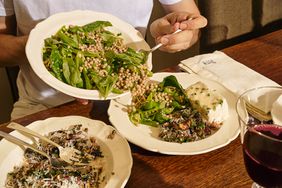 serving grain salad onto a plate with chard salad and poached halibut