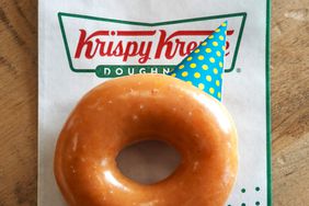 A Krispy Kreme glazed doughnut with a birthday party hat. 