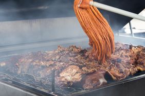 Sauce being applied to BBQ by mop.