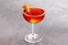 Old Pal cocktail in coupe class with orange peel garnish, on black marble background