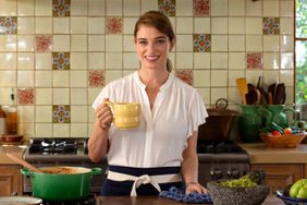 Chef Pati Jinich in a kitchen with a light yellow mug in her hand. 