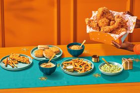 The Popeye's Festive Family Box on a table and in front of an orange wall.