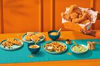 The Popeye's Festive Family Box on a table and in front of an orange wall.