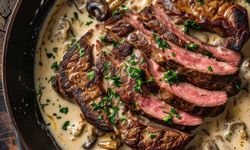 Steak with Cognac Cream Sauce. Traditional barbecue dry aged angus roast beef steak natural with mushrooms and onions in cream sauce served as top view in a classic skillet.