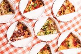 Slices of pizza on paper plates and a checkered red tablecloth at Pizza Marvin in Rhode Island.