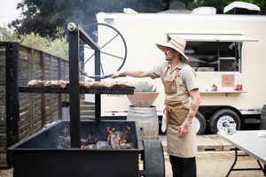 A cook working over an outdoor grill at Priedite Barbecue in Los Alamos.