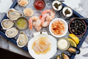 A variety of raw seafood and sauces on a tray with ice at Penny in New York City.