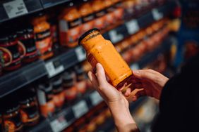 A person shopping for a sauce in a store. 